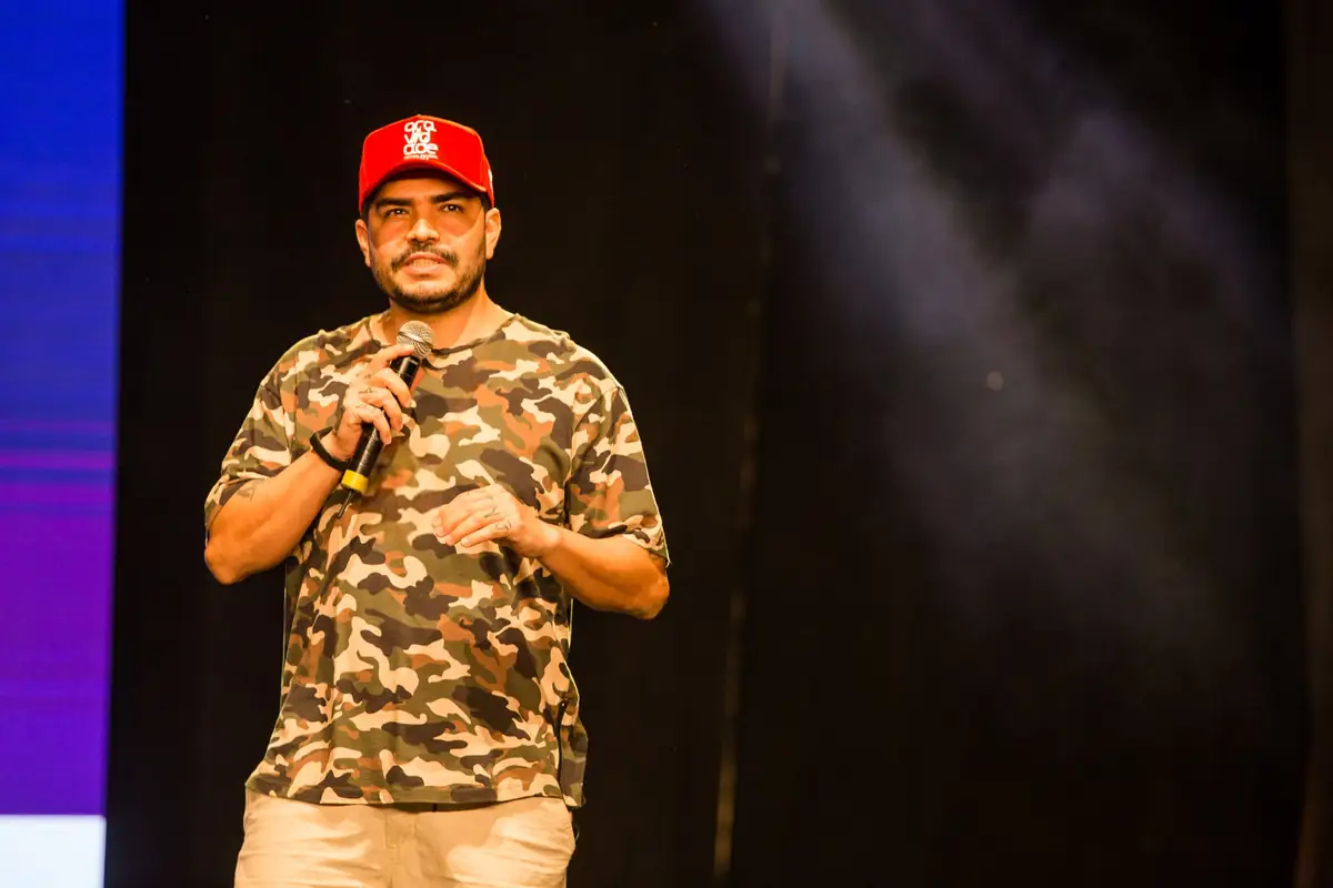 Ticko Bboy apresenta a palestra de marketing para artistas com microfone e camiseta camuflada